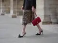 Elegancka kobieta w sukience w panterkę i czarnym blazerze, z czerwoną torebką Chanel. Czy sukienka w panterkę jest modna? Zdecydowanie tak!