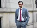 Elegancki mężczyzna w szarym garniturze i bordowym krawacie. Idealna stylizacja, jak ubrać się na komunię mężczyzna, by wyglądać szykownie.