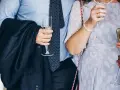 Elegancki mężczyzna w garniturze i krawacie, trzymający kieliszek szampana. To idealny strój, co się ubiera na bierzmowanie.