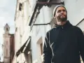Mężczyzna w czarnej bluzie z kapturem i czapce beanie patrzy w górę. Stylowy sposób, jak nosić bluzę z kapturem.