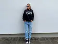 Dziewczyna w czarnej bluzie z kapturem i jeansach, idealny outfit, jak się ubrać na koncert hip hopowy.