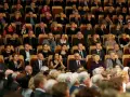 Elegancko ubrani ludzie siedzą w filharmonii. Panie w sukienkach, panowie w garniturach. To inspiracja, jak się ubrać do filharmonii.