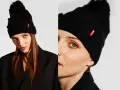 Czarna czapka zimowa z pomponem i wypukłymi kuleczkami, ozdobiona czerwonym logo. Idealna inspiracja, jak ozdobić czapkę zimową.