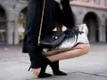 Kobieta w czarnej, puszystej bluzce i błyszczącej, **czarnej cekinowej spodnicy** z granatowymi akcentami, z czarną torebką na złotym łańcuszku.