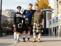 Trzech mężczyzn w tradycyjnych szkockich kiltach pozuje do zdjęcia na tle miejskiej zabudowy. Kto nosi kilt? Ci panowie!