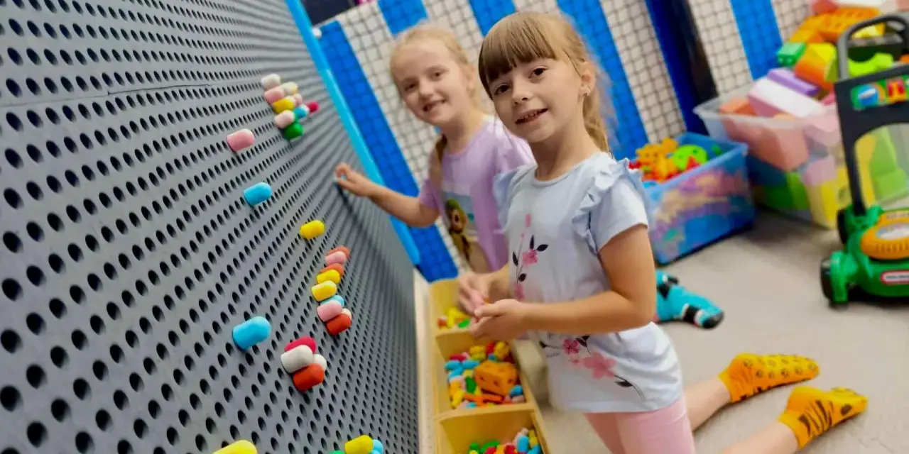 Dwie dziewczynki bawią się w sali zabaw. Idealny strój na urodziny do sali zabaw to wygodne ubranie i kolorowe skarpetki.