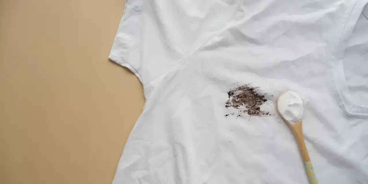 Biała koszulka z brązową plamą i łyżka sody oczyszczonej. Poznaj, jak usunąć żółte plamy z białych ubrań.