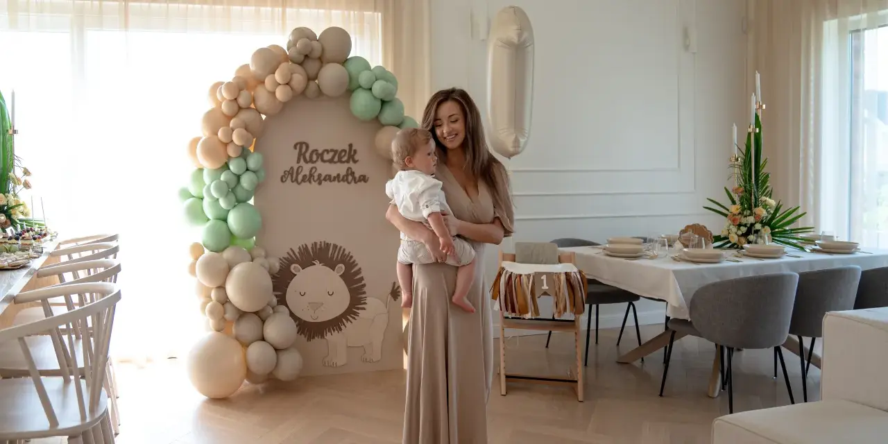 Elegancka sukienka i sandałki to świetny wybór, jak się ubrać na roczek jako gość. Uroczystość w stylu safari z lwem i balonami.