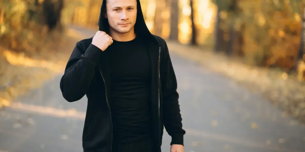 Mężczyzna w czarnej bluzie z kapturem i spodniami, idealny zestaw na fajne bluzy streetwear.