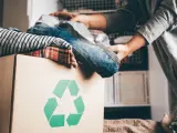 Pudełko z ubraniami i symbolem recyklingu. Wiesz, gdzie można oddać ubrania za darmo?