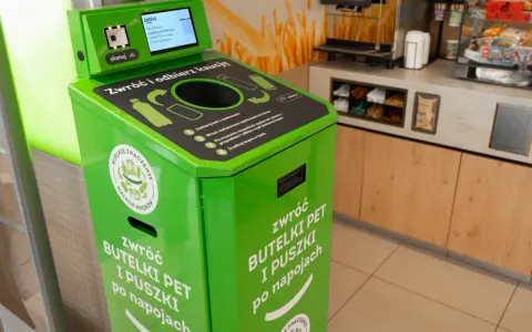 Zielony automat do zwrotu butelek PET i puszek. Skanuj kod, wrzuć opakowanie, by zdjąć zabezpieczenie sklepowe z butelki i otrzymać kaucy.