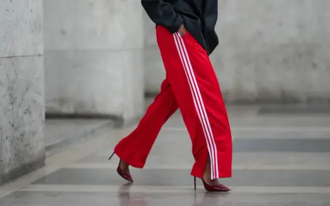 Czerwone spodnie dresowe z białymi lampasami i eleganckie szpilki. Odważne połączenie, które odpowiada na pytanie: jakie buty do dresów?