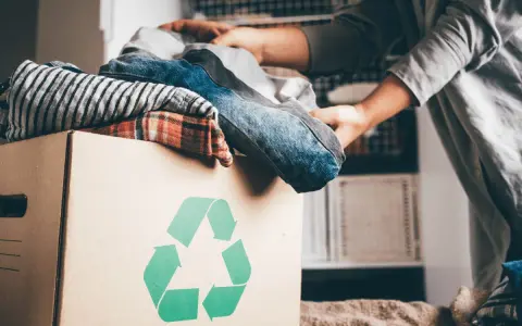 Pudełko z ubraniami i symbolem recyklingu. Wiesz, gdzie można oddać ubrania za darmo?