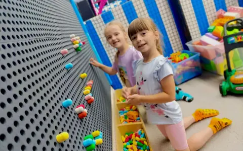 Dwie dziewczynki bawią się w sali zabaw. Idealny strój na urodziny do sali zabaw to wygodne ubranie i kolorowe skarpetki.