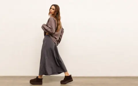 Modelka w luźnej, szarej spódnicy i brązowej bluzce. Idealny zestaw, który pokazuje, co pasuje do szarej bluzki.
