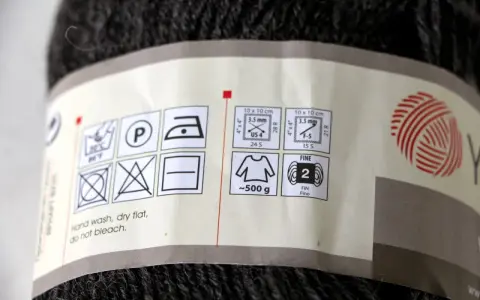 Etykieta na motku ciemnej włóczki informuje, że na jeden sweter potrzeba około 500 g materiału.