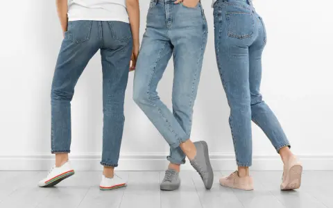 Trzy kobiety w jeansach i sneakersach. Dowiedz się, jak rozciągnąć jeansy, by były idealnie dopasowane.