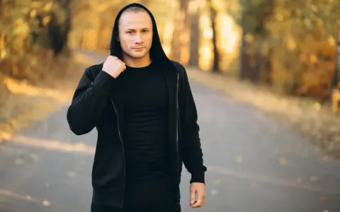 Mężczyzna w czarnej bluzie z kapturem i spodniami, idealny zestaw na fajne bluzy streetwear.