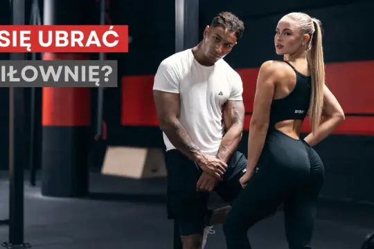 Jaki strój na siłownię? Para w sportowych ubraniach pozuje na tle siłowni.