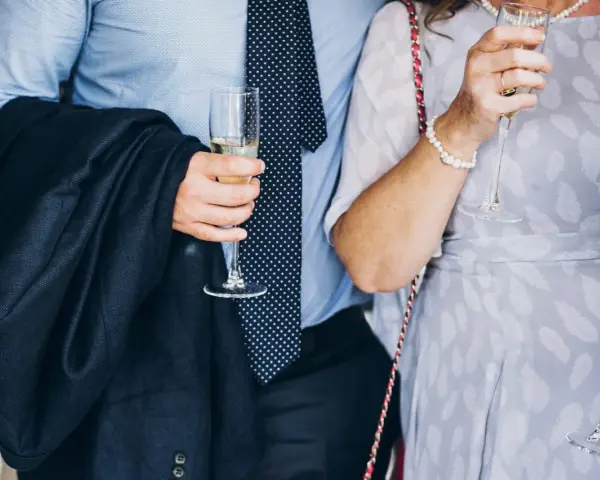 Elegancki mężczyzna w garniturze i krawacie, trzymający kieliszek szampana. To idealny strój, co się ubiera na bierzmowanie.