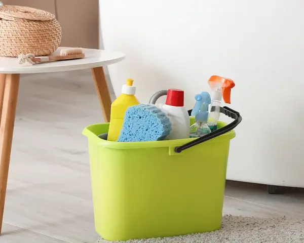 Wiadro z płynami do sprzątania i gąbką. Zastanawiasz się, jak sprać marker permanentny z ubrań? Te środki mogą pomóc!