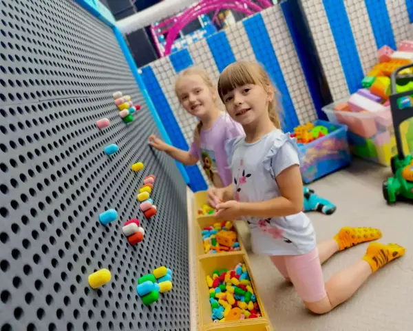 Dwie dziewczynki bawią się w sali zabaw. Idealny strój na urodziny do sali zabaw to wygodne ubranie i kolorowe skarpetki.