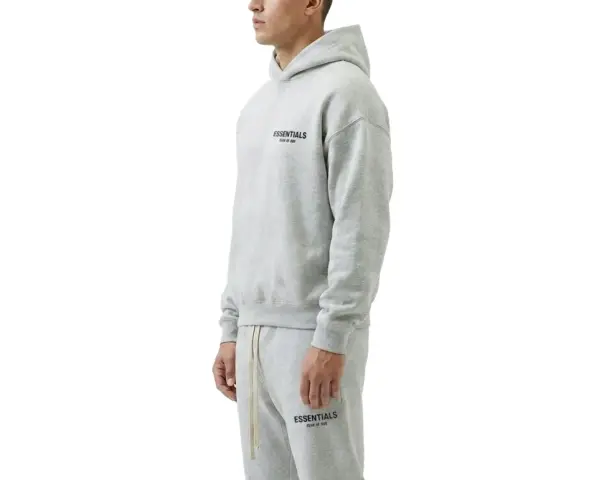 Szary komplet Essentials z kapturem i spodniami dresowymi. Zastanawiasz się, ile waży bluza Essentials? Jest lekka i wygodna.