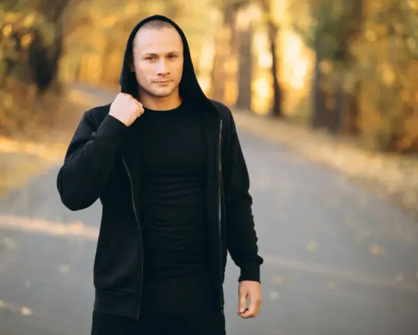 Mężczyzna w czarnej bluzie z kapturem i spodniami, idealny zestaw na fajne bluzy streetwear.