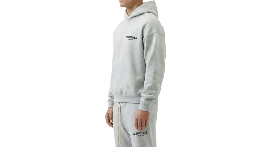 Szary komplet Essentials z kapturem i spodniami dresowymi. Zastanawiasz się, ile waży bluza Essentials? Jest lekka i wygodna.