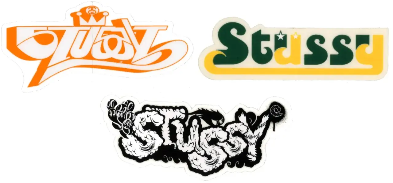 Naklejki z logo Stussy, firmy znanej z kultury streetwear. Jedna z nich to klasyczne zielono-żółte logo, druga w stylu graffiti.