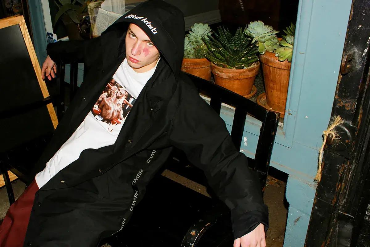 Młody mężczyzna w bluzie z kapturem i t-shircie z nadrukiem, prezentujący styl polskie marki odzieżowe streetwear.